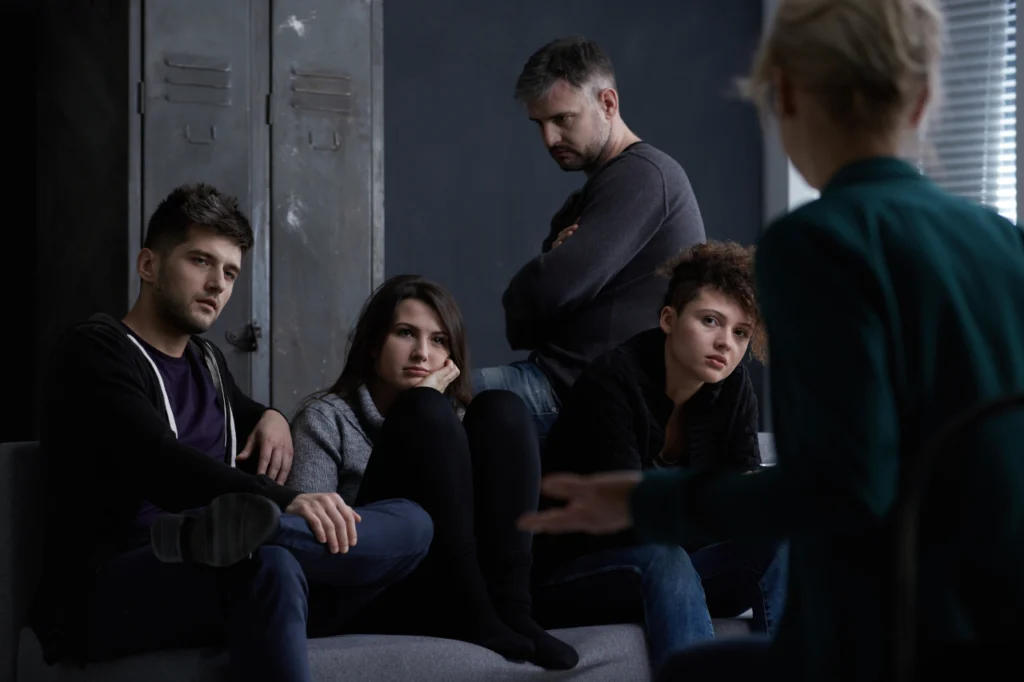 Unhappy looking people sit in an addiction recovery group