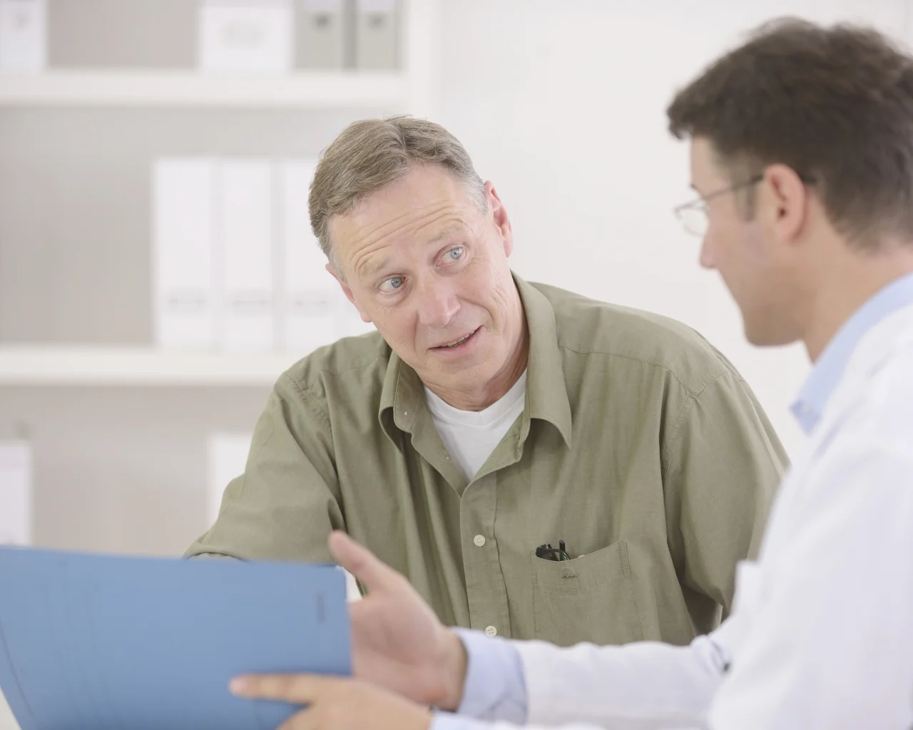 A slightly distraught man speaks with a doctor at the doctor's office