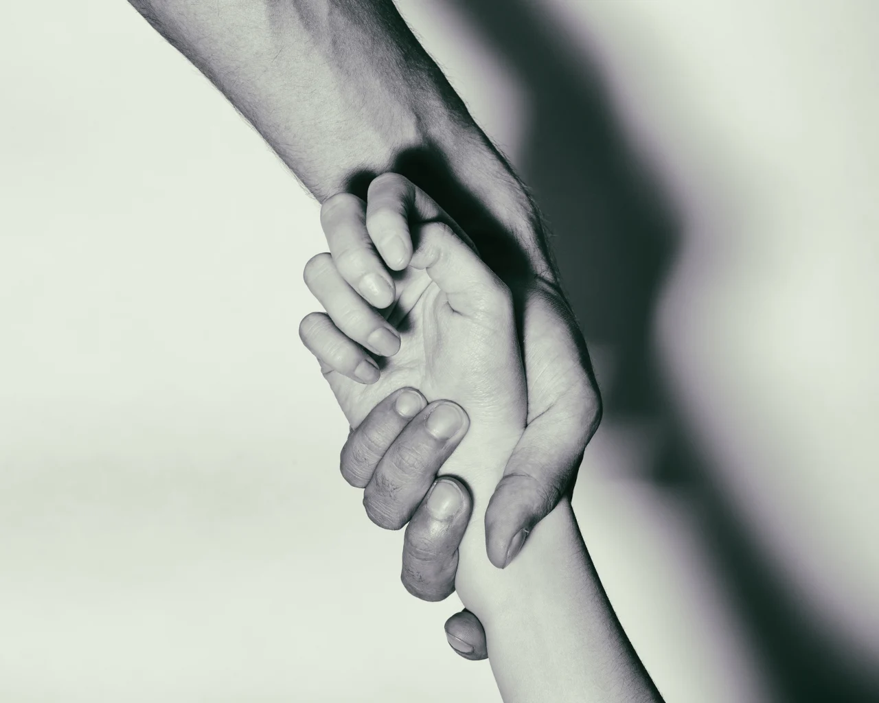 A person helps another by grabbing them by the wrist, pulling them upwards
