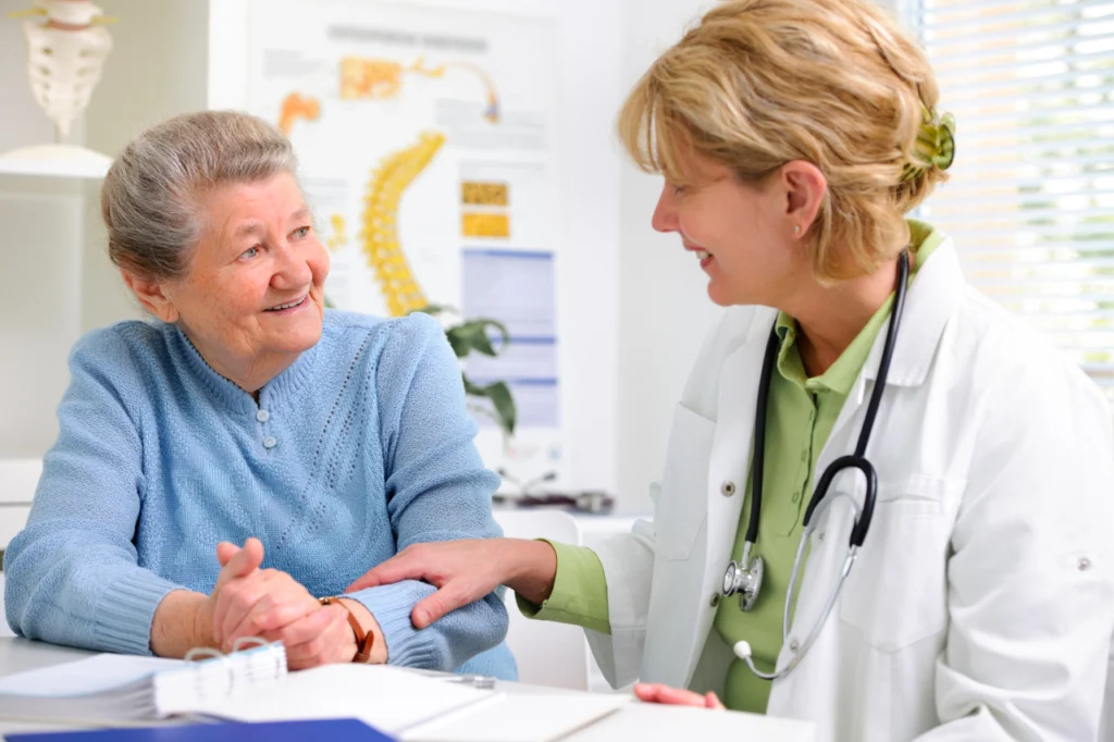A doctor speaks with an older patient during a consultation