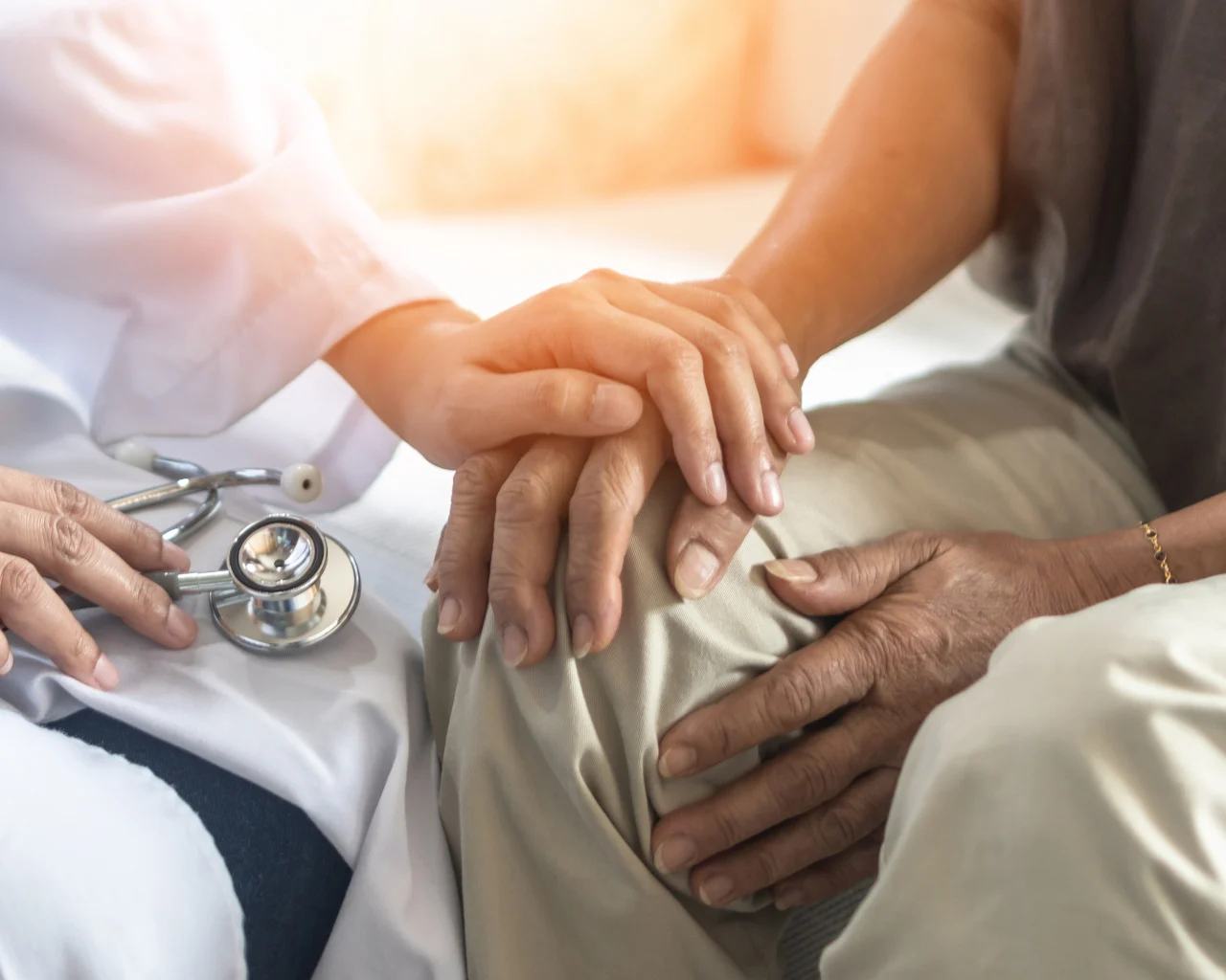 A doctor reassures a patient by gently gripping their hand