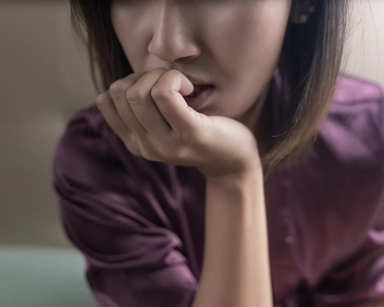 A woman anxiously bites at her fingernails