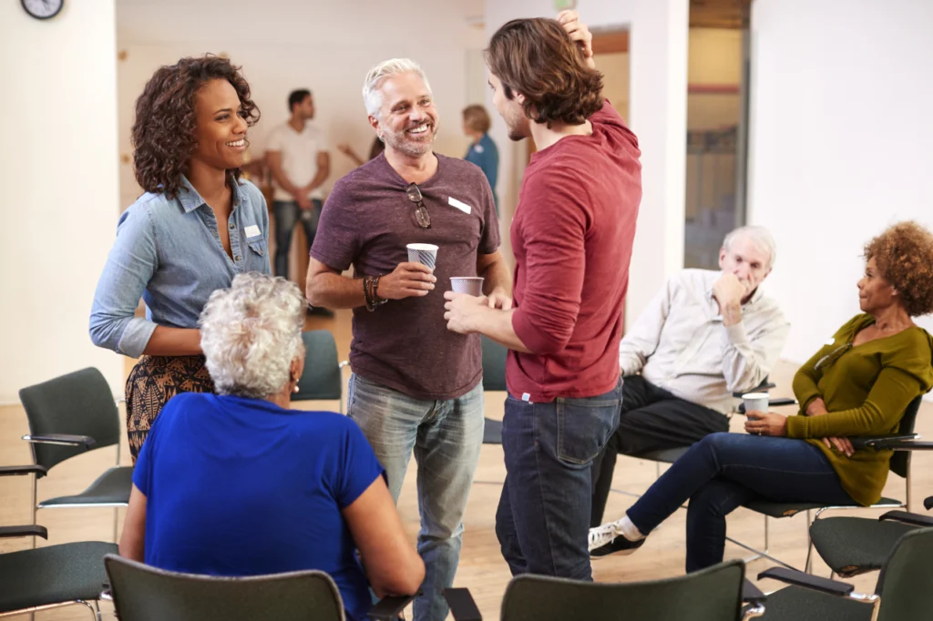 People smiling and talking at an addiction recovery support group