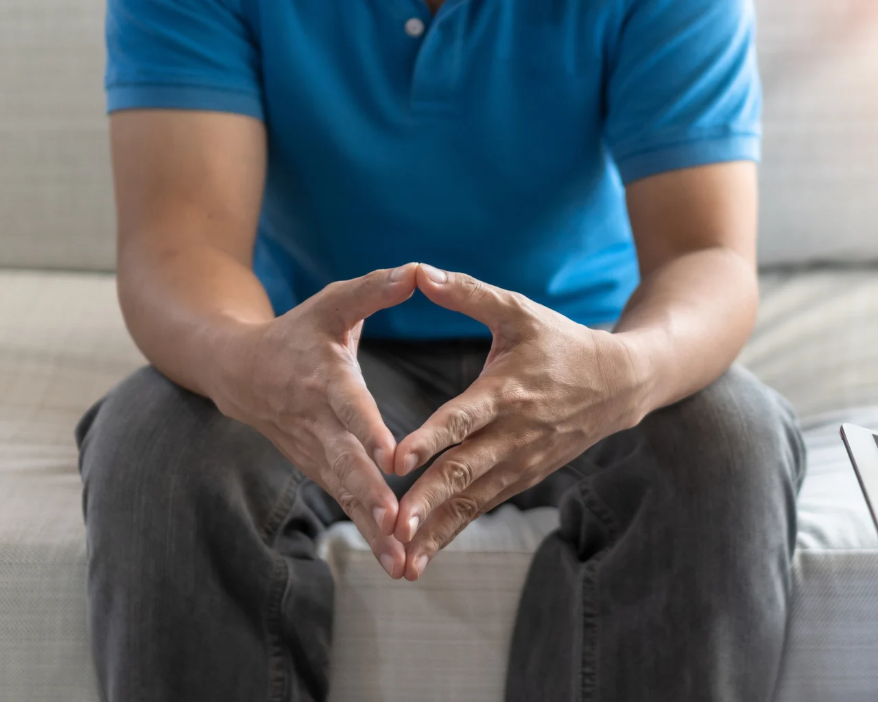 A man clutches his hands together inside a doctor's office
