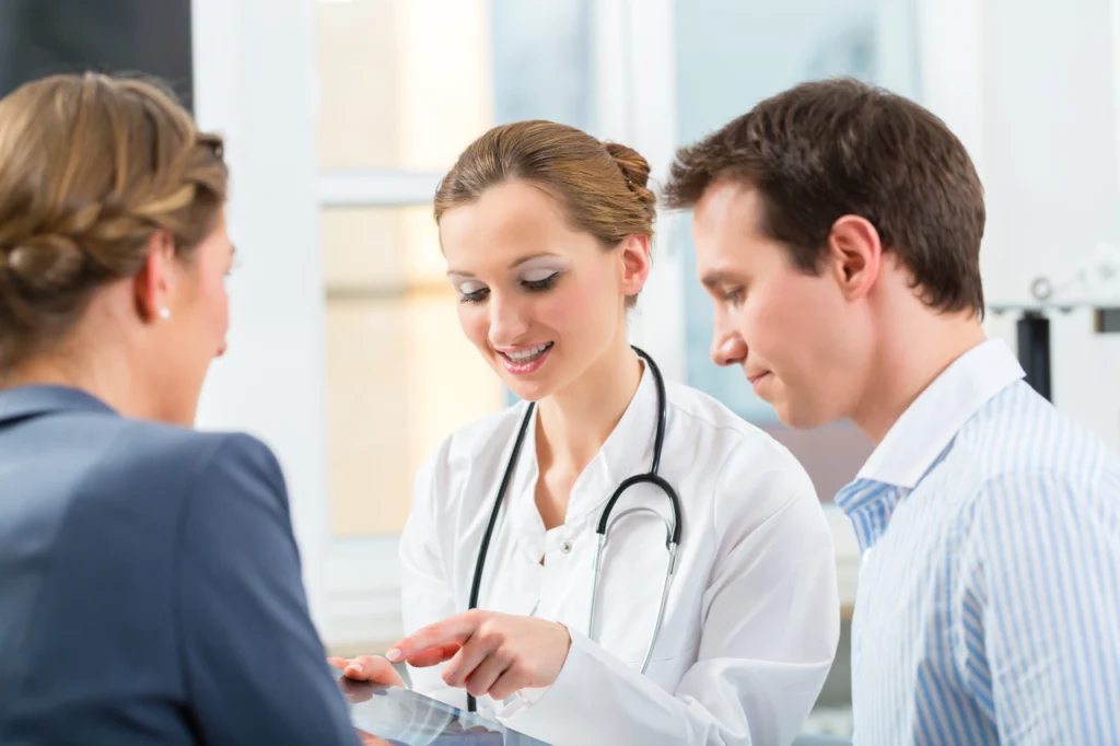 A doctor speaks with two people, explaining something during a consultation