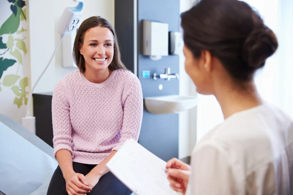 A woman smiles as she speaks with her doctor