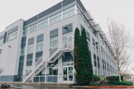 Exterior view of contemporary multi-story treatment facility with white facade, large windows, ivy-covered accent wall, and external staircase