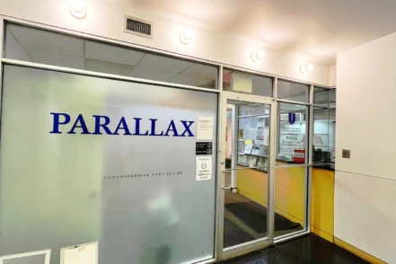 Interior main entrance showing frosted glass door with Parallax signage, reception area, and transparent glass partitions
