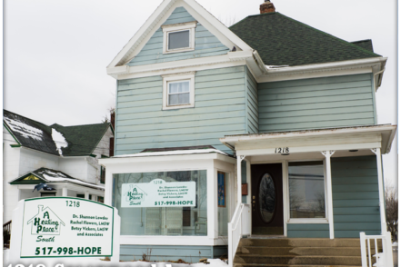Exterior view of light blue Victorian-style treatment center building with white porch, signage, and snow on ground