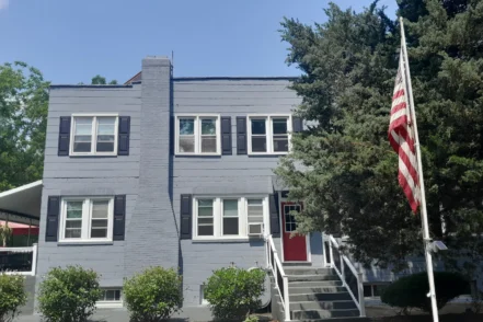 Exterior front view of brick treatment center building with American flag, entrance stairs, and landscaping