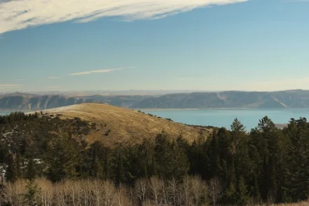Exterior landscape view showing forested mountains, lake, and distant valleys under clear sky
