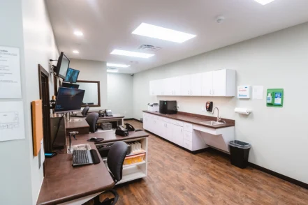 Interior clinical office with computer workstations, medical cabinetry, and equipment for patient consultations