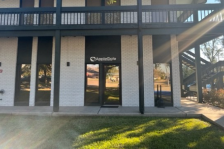 Exterior view of modern two-story white brick treatment facility with dark railings, covered porch entry, and AppleGate signage on glass doors