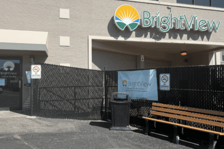 Exterior view of BrightView treatment center main entrance with logo signage, entrance door, and black metal fencing