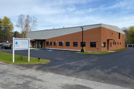 Exterior view of Saint Joseph's ATRC Saranac Lake Outpatient Clinic showing brick and stone facade, entrance, parking area, and landscaping
