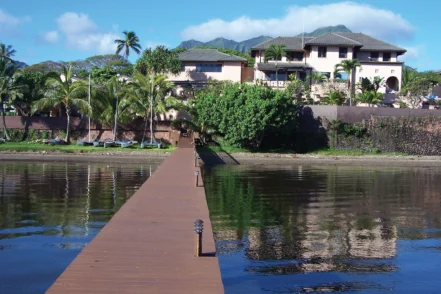 Exterior showing main building entrance facing water with wooden dock, palm landscaping, and mountain views